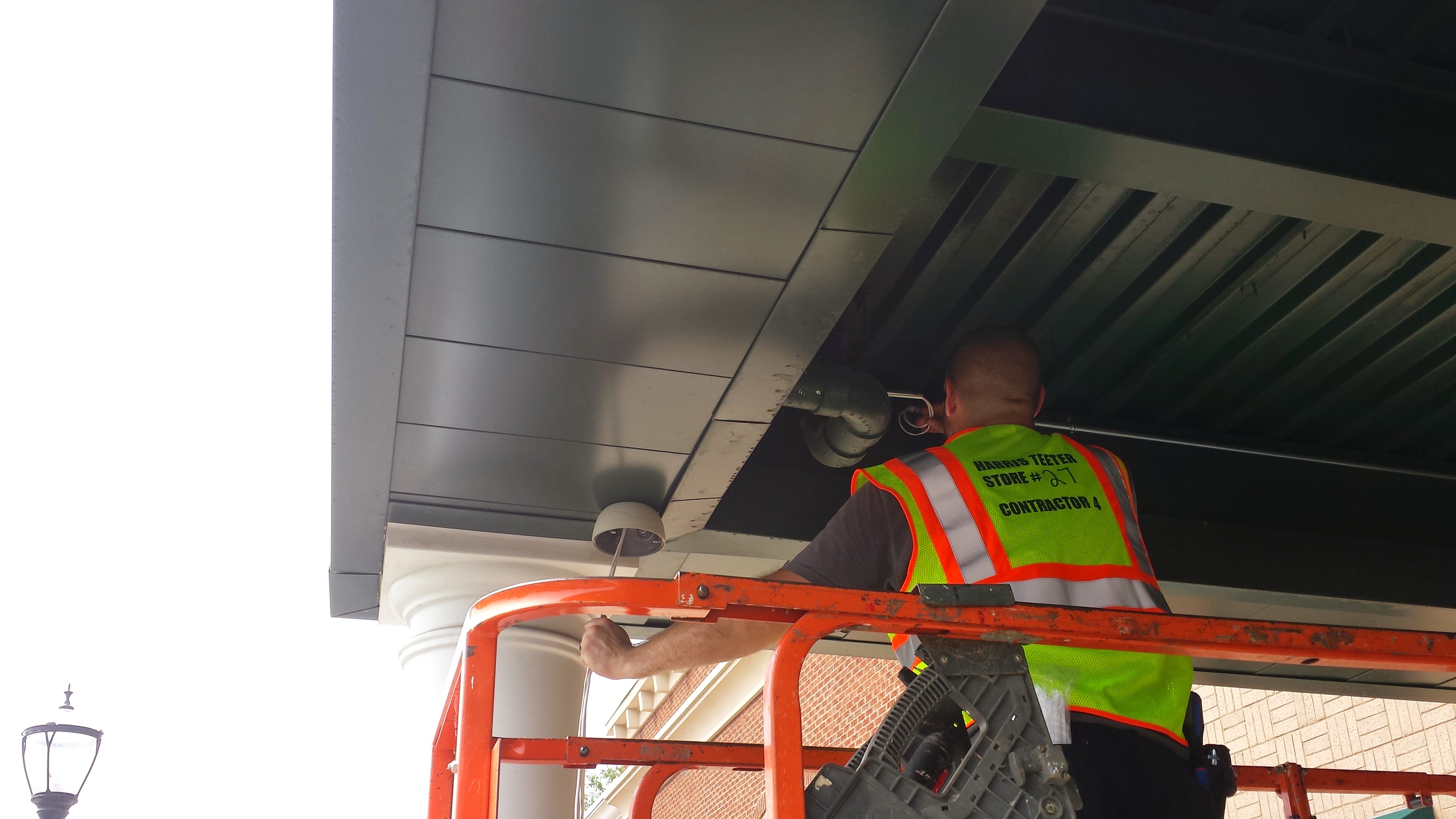 Security Consult technician installing a camera from a lift on a Charlotte commercial job